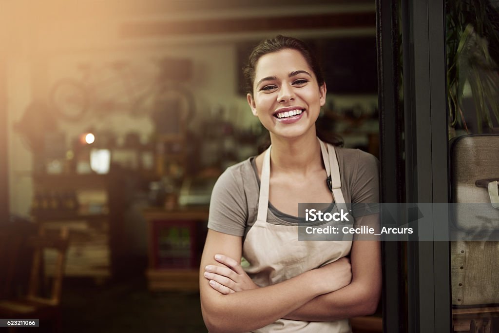 Pop in to your local coffee parlor Portrait of a confident young woman standing in the doorway of a coffee shop Women Stock Photo