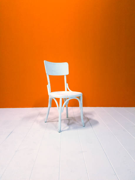 istock White wooden chair and orange painted wall 623213920