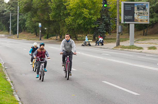 active young father with son and daughter having bicycle ride - solicitous imagens e fotografias de stock