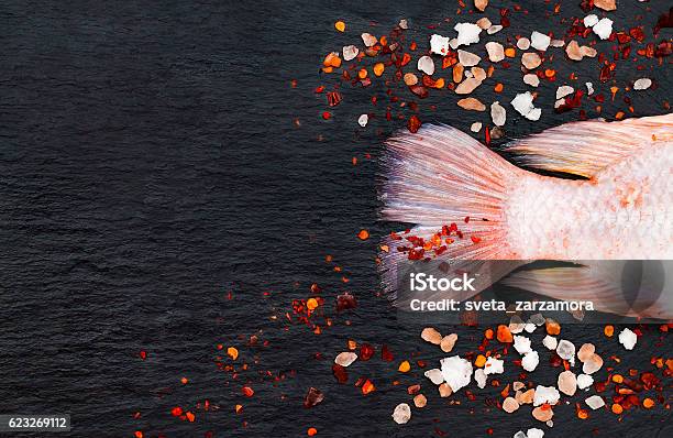 Tilapia Fish On Black Board With Spices Culinary Seafood Background Stock Photo - Download Image Now
