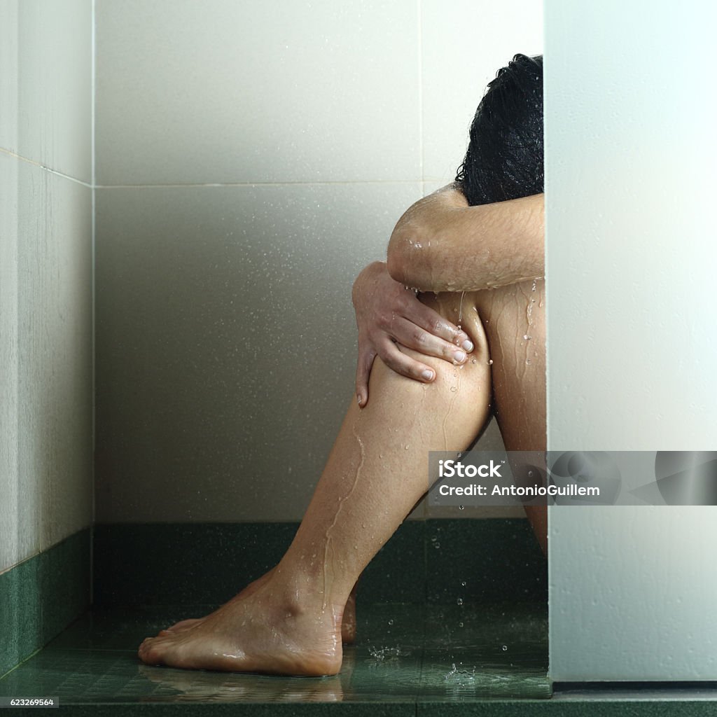 Sad woman after abuse in shower Sad woman after abuse crying under the water in the shower Sexual Assault Stock Photo