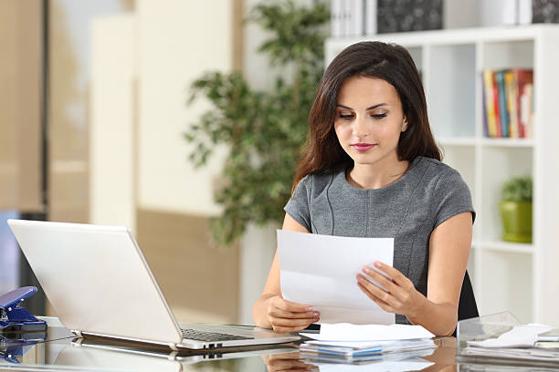 businesswoman reading a letter at office - opening mail letter envelope imagens e fotografias de stock