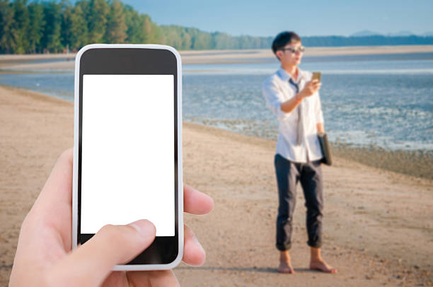 Asian Business man relaxing on beach using laptop and smartphone