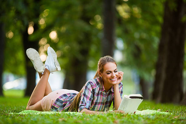 istock Beautiful smiling woman reading an interesting book in park. 623271370