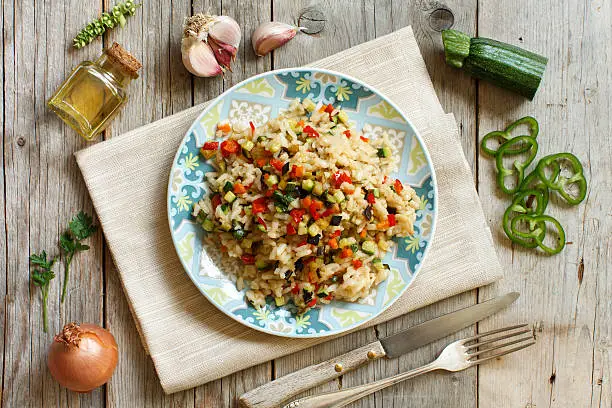 Risotto with vegetables on a wooden table top view