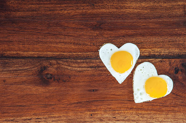 istock Two heart-shaped fried eggs on a wooden background 623274872
