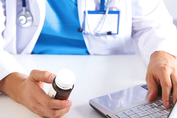 istock the doctor writes a prescription pill on the computer 623274928