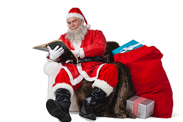 istock Santa reading bible with sack of christmas present beside him 623286574