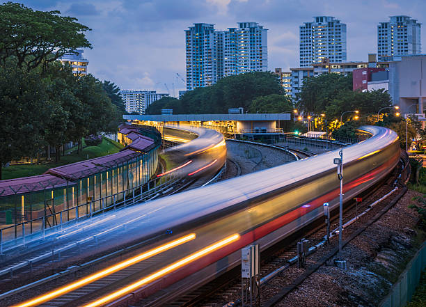 MRT trains entering and leaving AMK station Mass Rapid Transit (MRT) trains arriving and leaving the station of Ang Mo Kio in Singapore. The image was taken in the evening during blue hour and the trains have motion blur. public transportation stock pictures, royalty-free photos & images