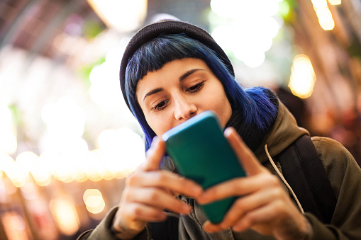 Mujer joven que usa un teléfono inteligente al aire libre photo