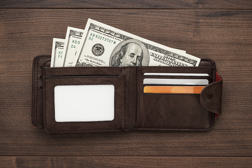 men's purse with money, credit and debit cards on the wooden table