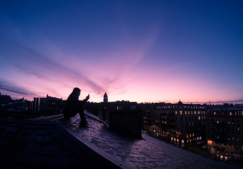A young man sitting alone on a rooftop in Gothenburg, Sweden. Shot during sunset.