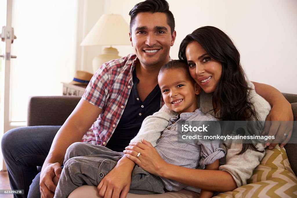 Portrait Of Happy Family Sitting On Sofa In at Home Family Stock Photo