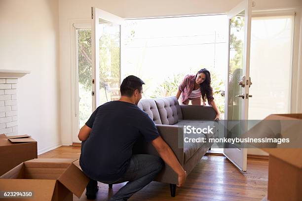 Couple Carrying Sofa Into New Home On Moving Day Stock Photo - Download Image Now - Relocation, Furniture, Sofa