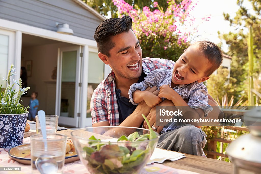 Pai e filho comendo comida ao ar livre no jardim juntos - Foto de stock de Família royalty-free