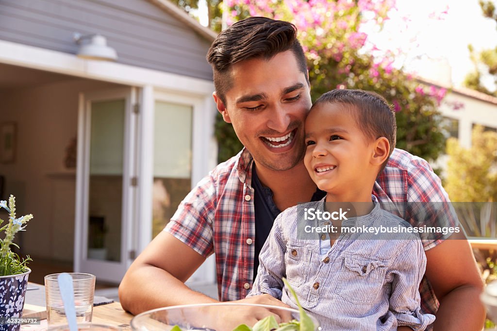 Padre e hijo comiendo comida al aire libre en el jardín juntos - Foto de stock de Etnia Latinoamericana libre de derechos