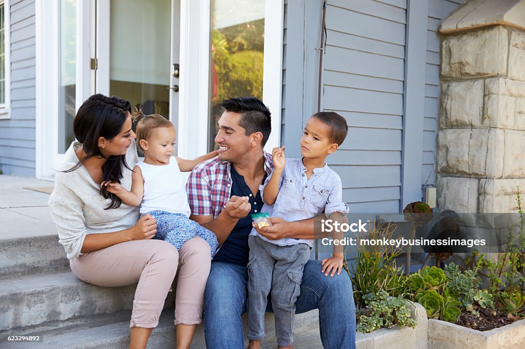 Father Giving Children Candy On Steps Outside Hose Family Stock Photo