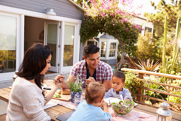 Family Saying Grace Before Outdoor Meal In Garden Family Saying Grace Before Outdoor Meal In Garden saying grace stock pictures, royalty-free photos & images