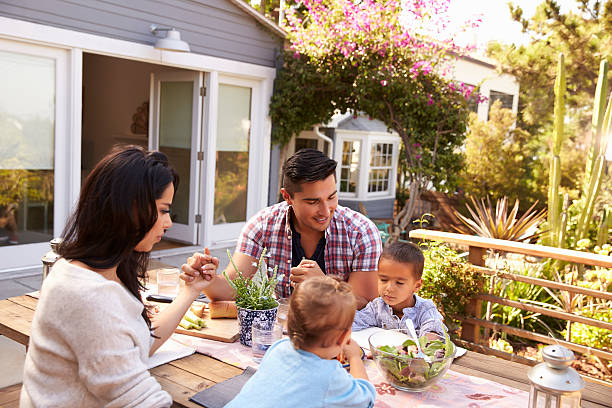 семья говоря благодать перед едой на открытом воздухе в саду - saying grace стоковые фото и изображения