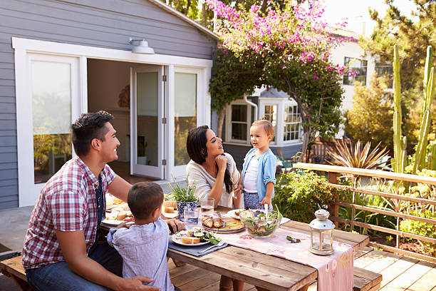 Family At Home Eating Outdoor Meal In Garden Together Family At Home Eating Outdoor Meal In Garden Together family at home stock pictures, royalty-free photos & images