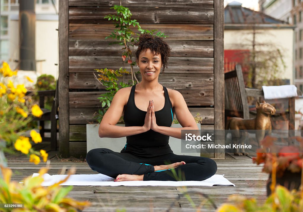 Urban yoga Young african American woman practicing yoga on a rooftop garden in NYC. the lotus position. Yoga Stock Photo