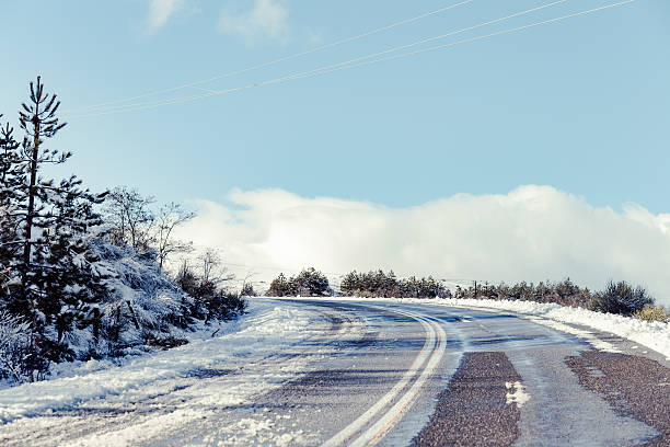 Winter scenic of slippery and wet rural mountain road with snow on sunny day