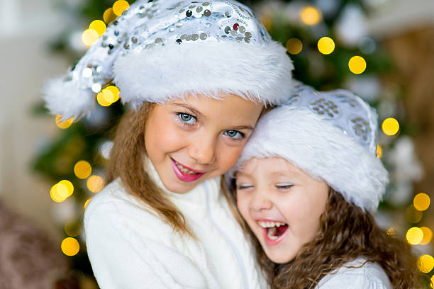 istock Two girl, gift, Christmas tree, white hats 623298110