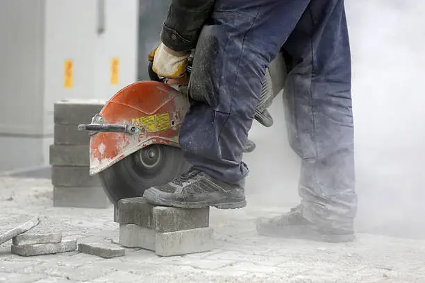 Worker uses a stone cutter to cut the brick pavers. Cutting concrete paving stabs using a cut-off saw. Paving stone saws working with power tools.