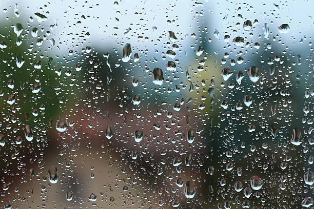 istock Rain drops on window with house and church in background 623302350