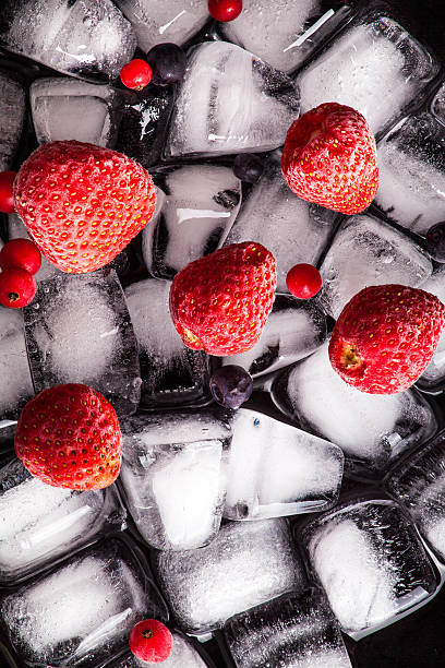 istock Frozen strawberries and cranberries lying on ice cube. Dark background 623307140