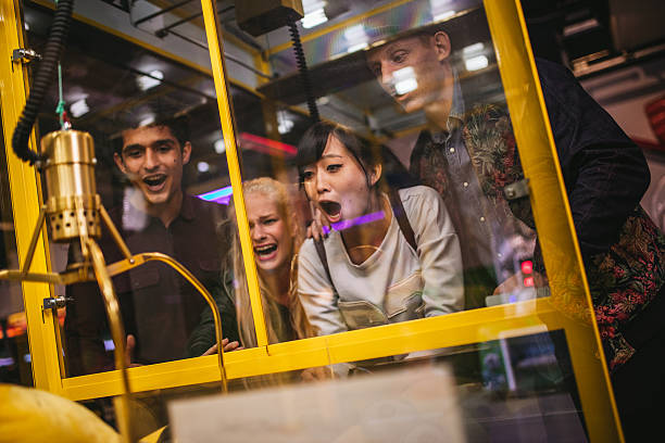 Excited young friends playing toy grabbing game Excited young friends playing toy grabbing game at amusement park. Happy woman selecting a random soft toy in a vending machine. vending machine photos stock pictures, royalty-free photos & images
