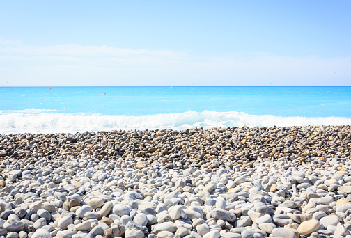 Gray sand and stones close-up on the beach. Stone in the foreground. Beach in winter. Sea coast soil. Beach resort atmosphere