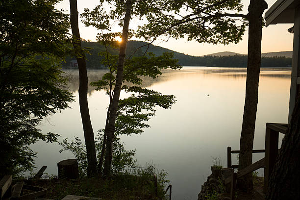 Sunrise at Mountain View Lake in Sunapee, New Hampshire, with trees and reflections.