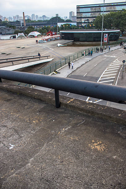 Concrete overpass with green metal railing seen from below against cloudy sky