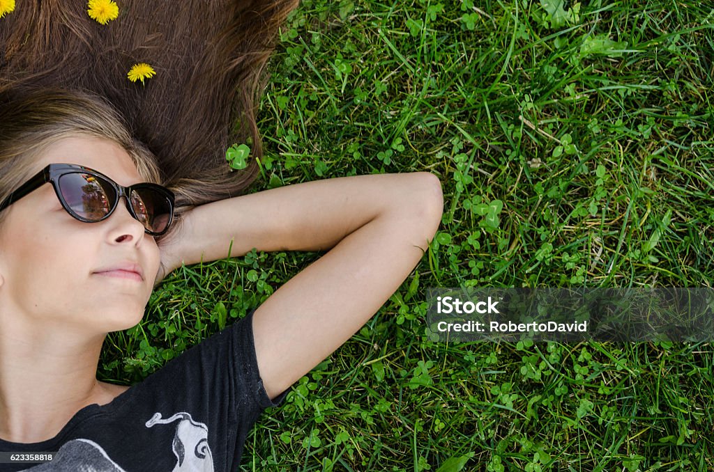 adolescente con elegantes gafas de sol tumbadas sobre hierba verde - Foto de stock de Chica adolescente libre de derechos