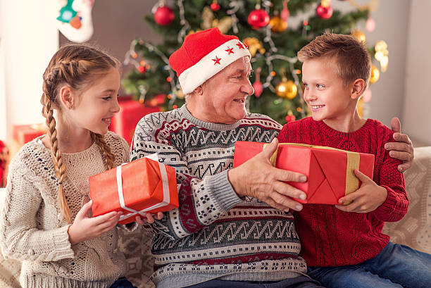 istock Old man sharing Christmas gifts with children 623360446