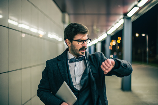 Nervous man being late and watching at hand clock