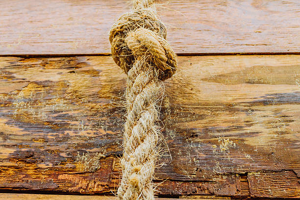 istock Thick jute rope with a knot hanging from wooden planks 623365072
