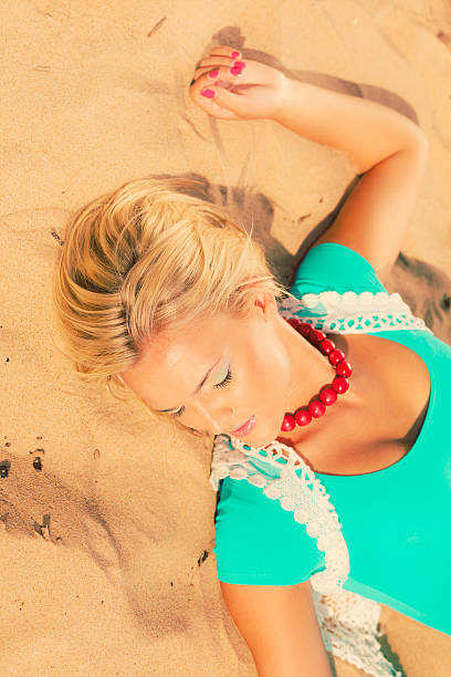 istock Blonde woman lying on sand. 623365322