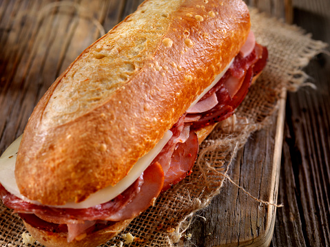 Iberian ham sandwich on a dark-colored tray, all highlighted by a light border on a black background