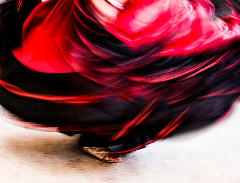 Abstract of traditional dancer wearing a colorful red skirt and leather sandals.  Intentional motion blur.  The woman is performing a Costa Rican folkloric dance in traditional costume.