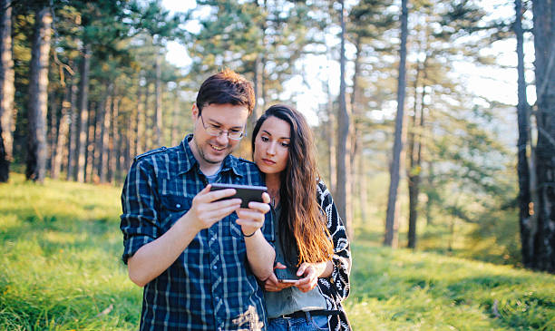 istock Young couple walking and using smartphone in the woods 623367724
