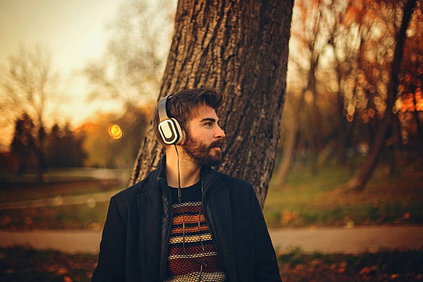 istock Bearded man leaning on tree in a park at sunset 623367950