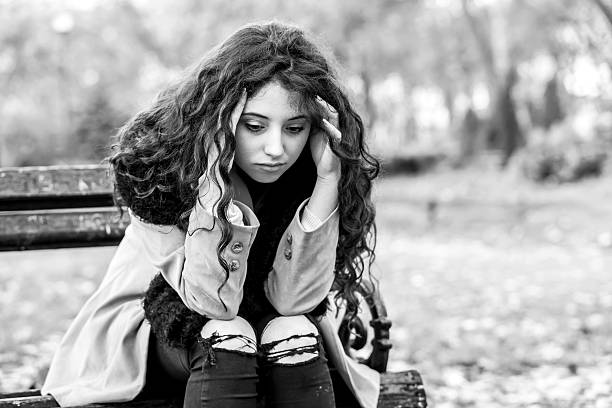 istock sad woman sitting on bench in a park 623370250