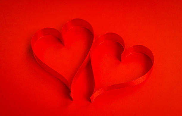 istock Red ribbon making the shape of heart on red background 623373804