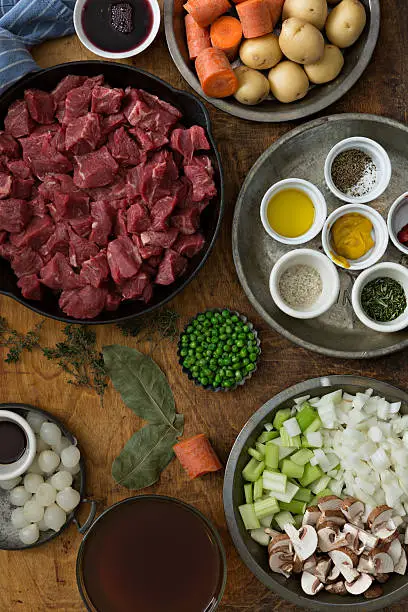 An overhead close up vertical photograph with all the makings for a delicious beef stew.