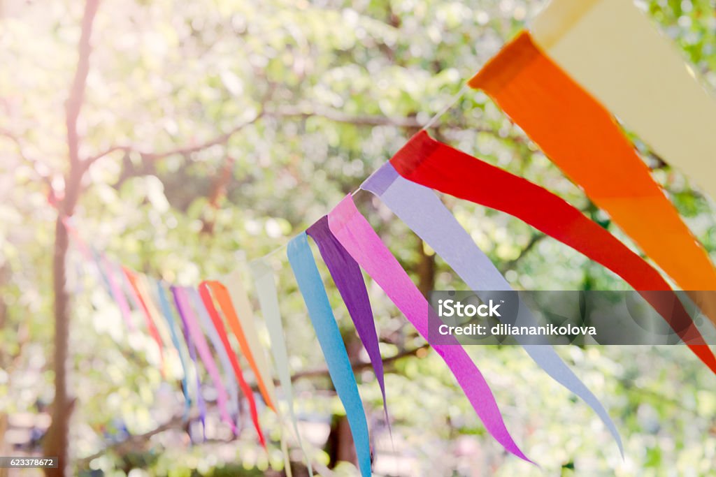 Closeup of a colorful party banner tied between trees. Close up of a colorful party banner tied between trees in a park at an open air celebration event. Traditional Festival Stock Photo