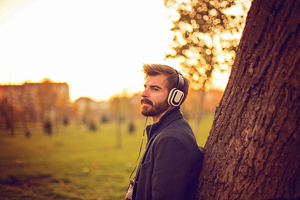 istock Bearded man leaning on tree in a park at sunset 623380680