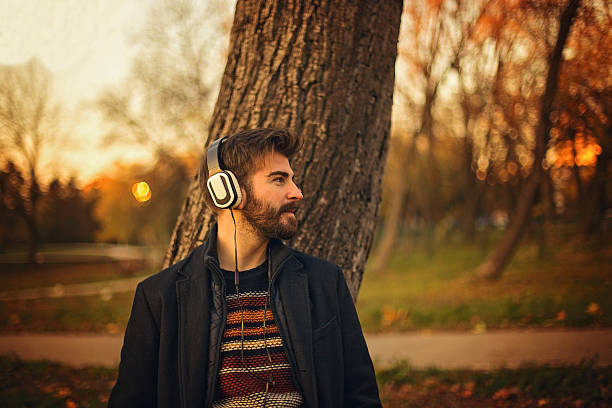 istock Bearded man leaning on tree in a park at sunset 623380718