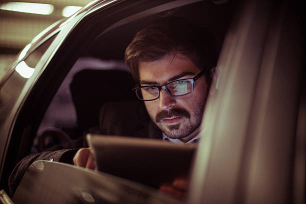 istock Businessman using modern digital tablet in the car at night 623383498